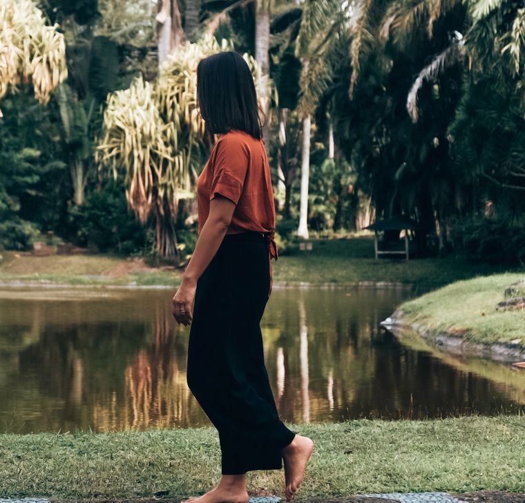 Sabrina walking barefoot beside a pond under palm trees